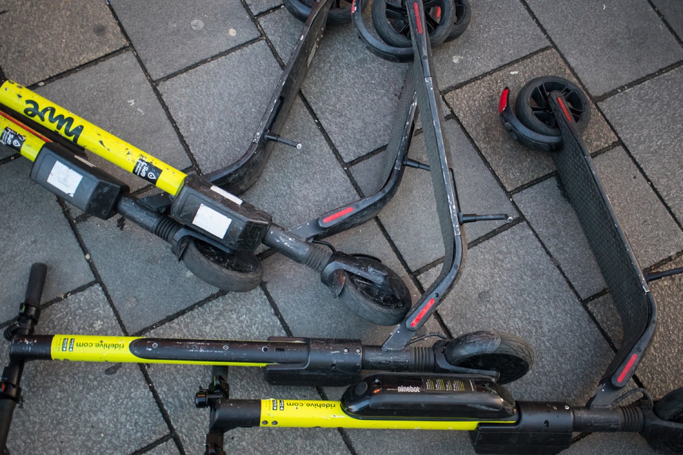 Rental scooters lying flat on the pavement — fails the stability check.