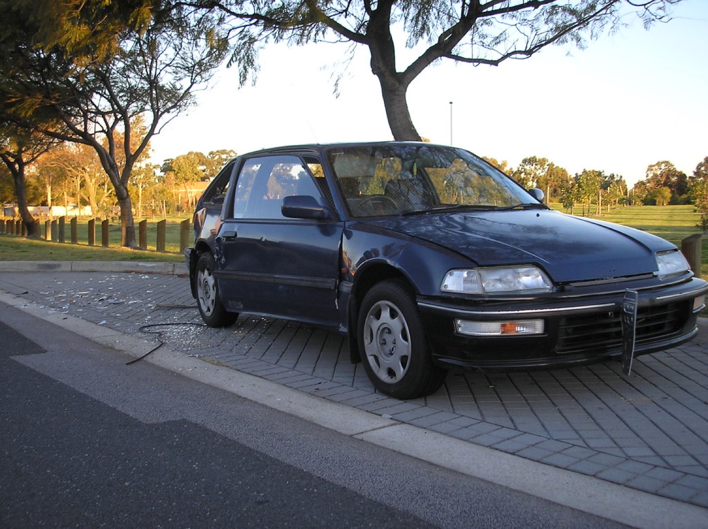 Hatchback with crushed side panels and broken glass on the ground — should fail.